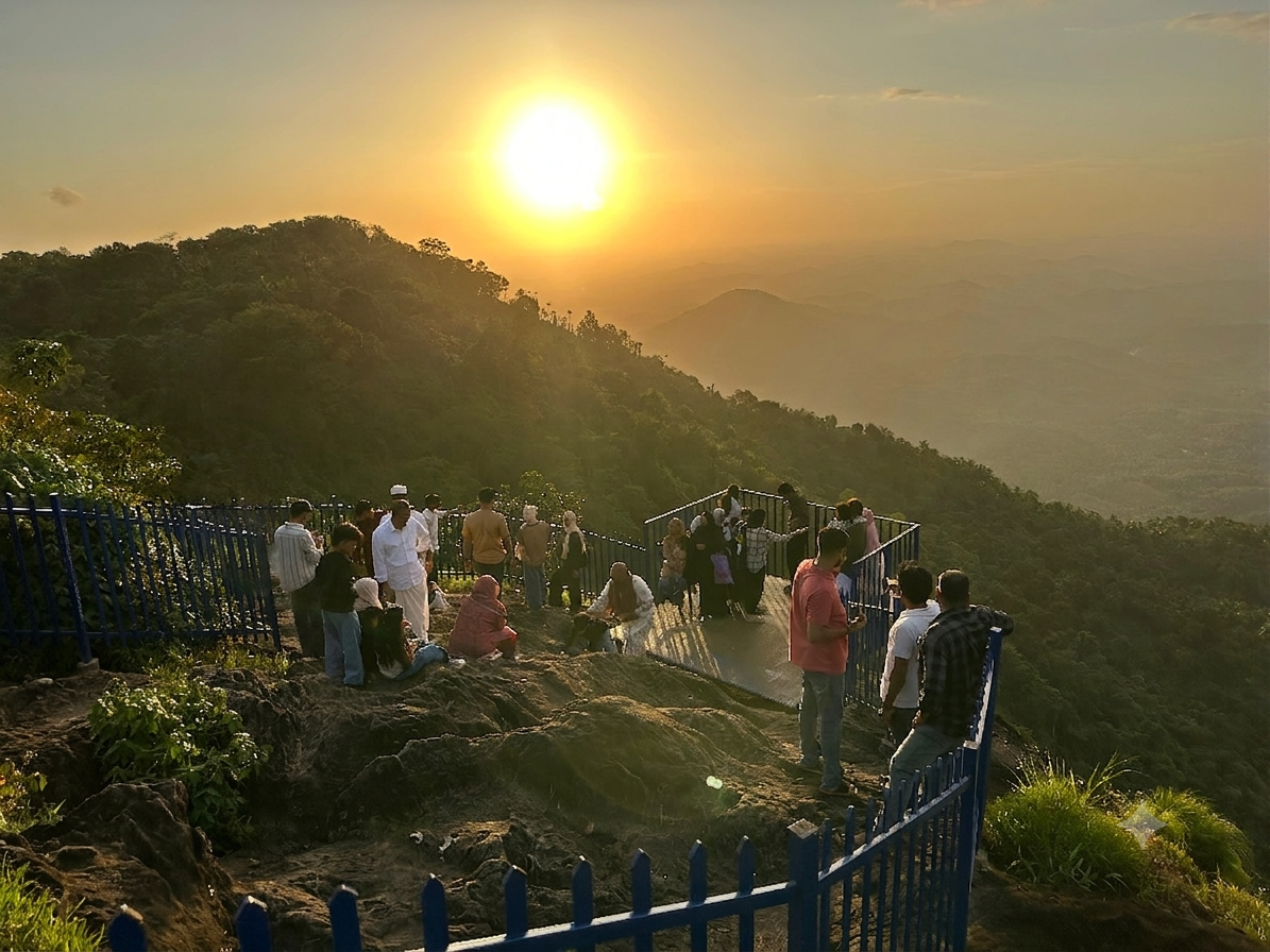 Visitors watching the sunset from a Vayalada viewpoint, overlooking mist-layered hills